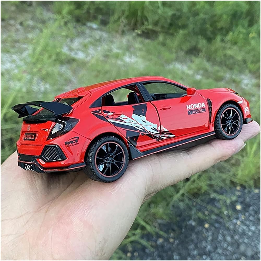 Red Honda model car held in a hand with a blurred natural background